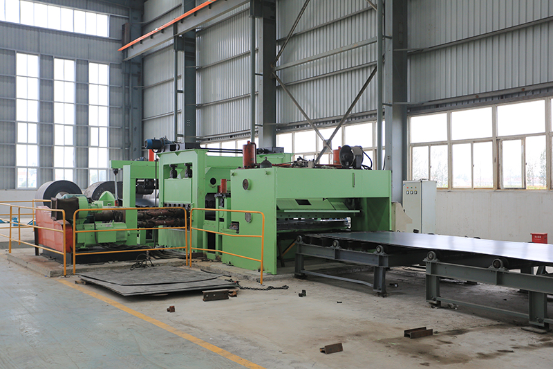 Green metal-processing machine in a bright industrial warehouse with safety railings, no people